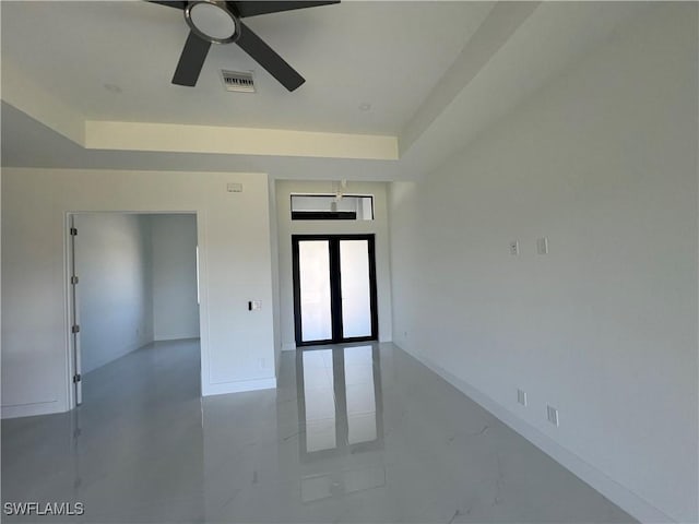 spare room with ceiling fan, visible vents, baseboards, french doors, and a raised ceiling