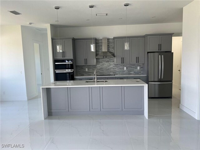 kitchen with a sink, wall chimney range hood, gray cabinets, and freestanding refrigerator