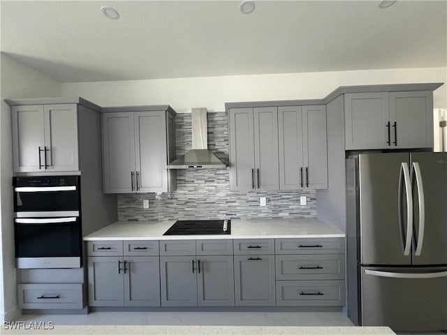 kitchen with light countertops, decorative backsplash, gray cabinetry, black appliances, and wall chimney exhaust hood