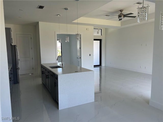 kitchen with a sink, visible vents, marble finish floor, freestanding refrigerator, and a tray ceiling