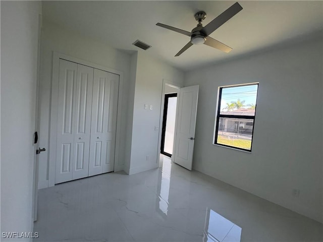 unfurnished bedroom featuring marble finish floor, a ceiling fan, visible vents, and a closet