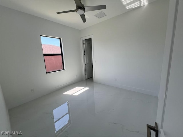 empty room with a ceiling fan and marble finish floor