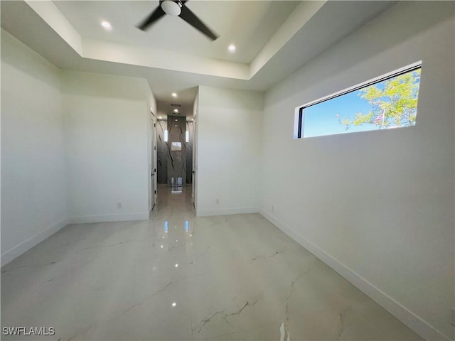 empty room featuring baseboards, a raised ceiling, a ceiling fan, and recessed lighting