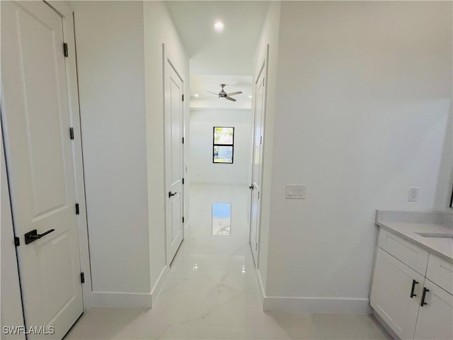 corridor featuring marble finish floor, baseboards, and recessed lighting