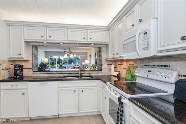 kitchen featuring white appliances, backsplash, a sink, and white cabinets