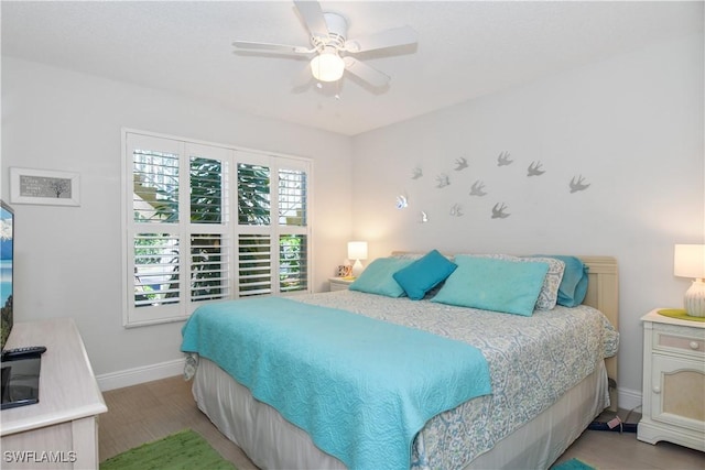 bedroom with ceiling fan, wood finished floors, and baseboards