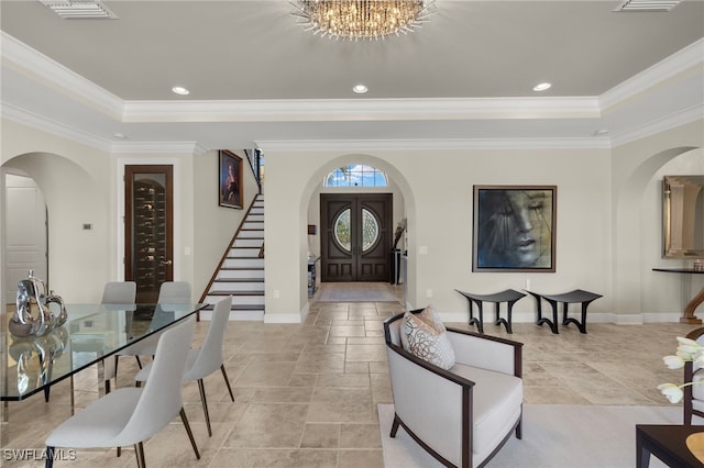 foyer entrance featuring crown molding, arched walkways, stairs, and a tray ceiling