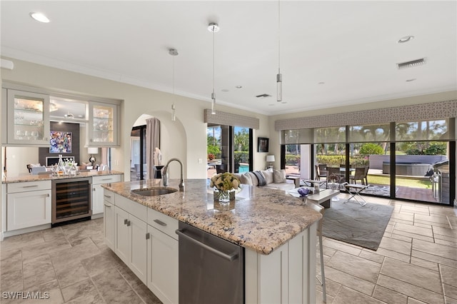 kitchen featuring crown molding, arched walkways, a sink, open floor plan, and wine cooler