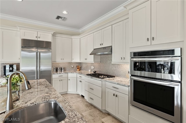 kitchen with visible vents, a sink, under cabinet range hood, appliances with stainless steel finishes, and crown molding