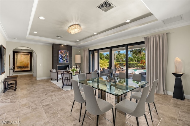 dining area featuring visible vents, baseboards, a tray ceiling, ornamental molding, and arched walkways