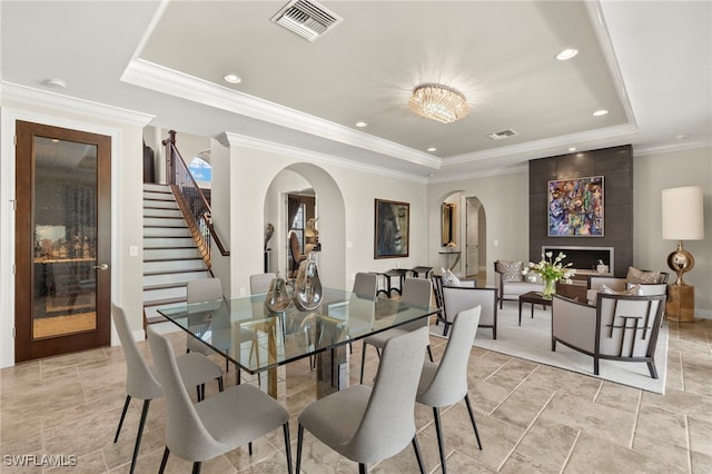 dining space featuring a tray ceiling, arched walkways, visible vents, and ornamental molding