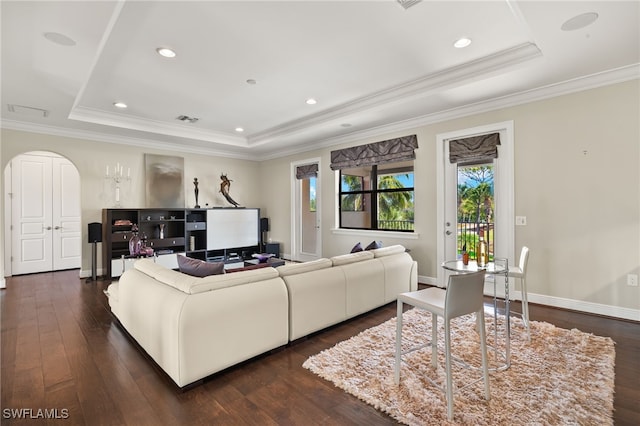 living room featuring dark wood finished floors, a tray ceiling, baseboards, and arched walkways