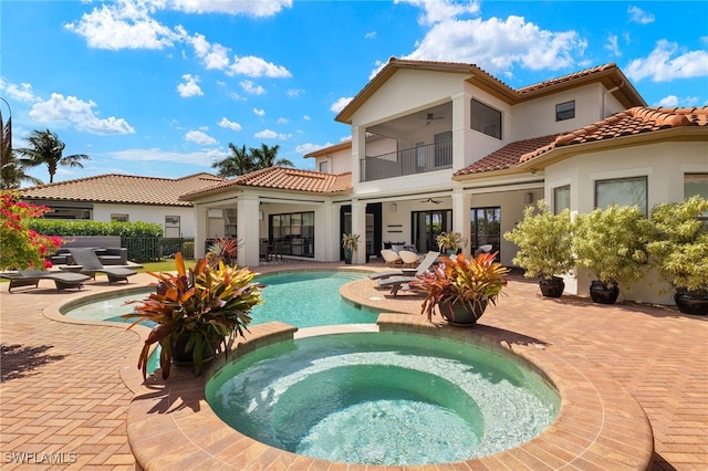 rear view of property with ceiling fan, a tile roof, a patio area, a balcony, and stucco siding