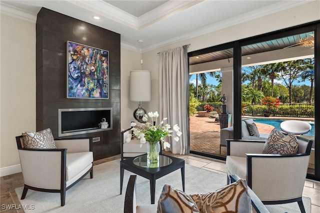 living area featuring crown molding, light tile patterned flooring, baseboards, and a raised ceiling