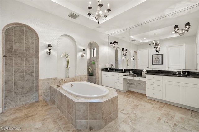 bathroom with vanity, visible vents, an inviting chandelier, a raised ceiling, and a bath