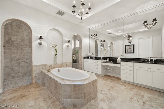 full bathroom featuring a notable chandelier, vanity, a tray ceiling, visible vents, and a bath
