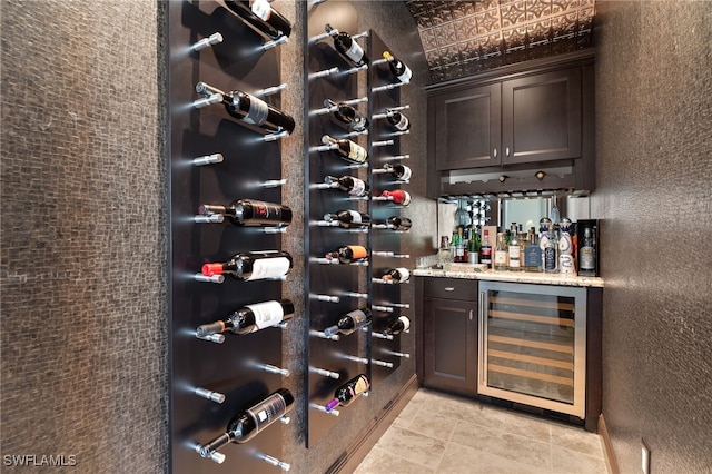 wine cellar featuring a dry bar, a textured wall, wine cooler, and light tile patterned flooring