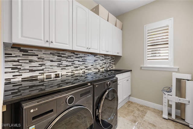 washroom with baseboards, a sink, cabinet space, and washing machine and dryer