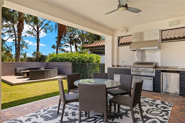 view of patio / terrace featuring outdoor dining space, a grill, exterior kitchen, ceiling fan, and a hot tub