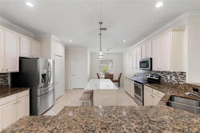 kitchen featuring appliances with stainless steel finishes, decorative light fixtures, crown molding, a center island, and sink