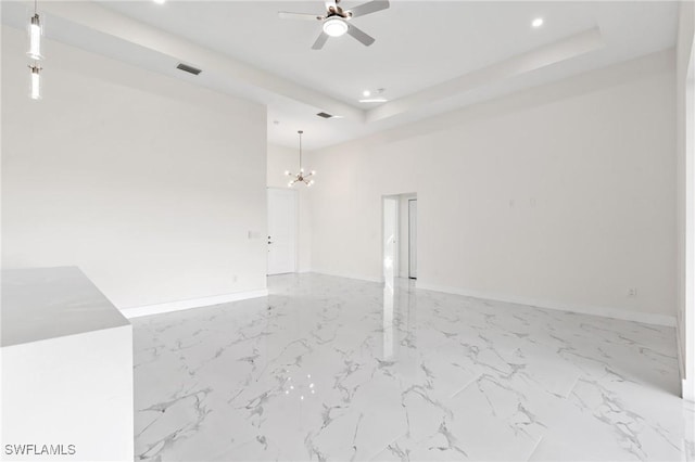 spare room with a raised ceiling, visible vents, marble finish floor, and ceiling fan with notable chandelier