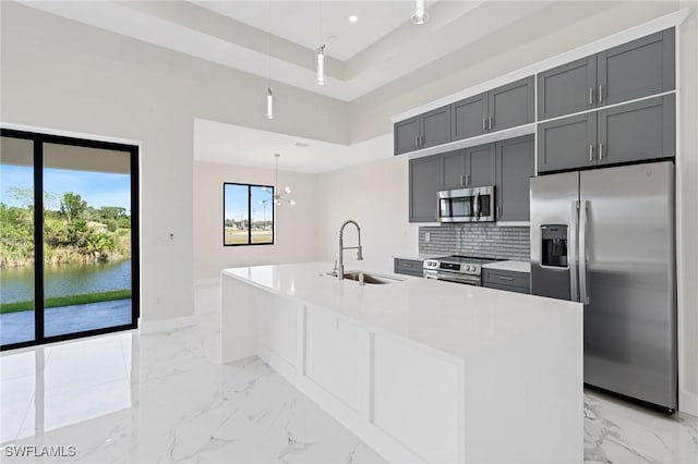 kitchen with stainless steel appliances, a water view, a sink, hanging light fixtures, and light countertops