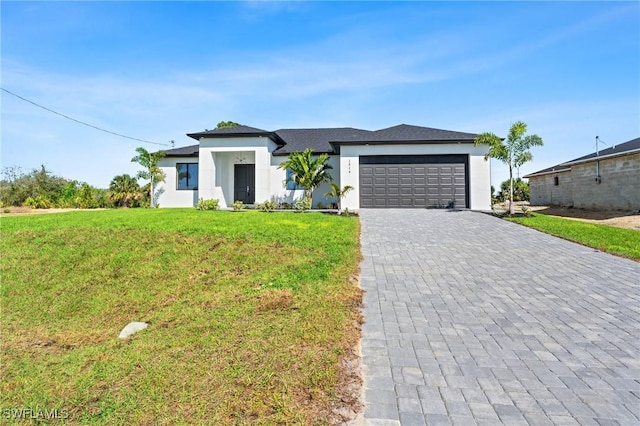 prairie-style home featuring decorative driveway, an attached garage, a front lawn, and stucco siding