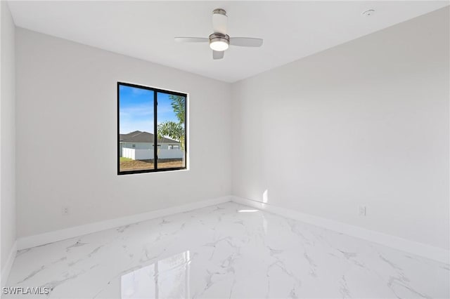 empty room with marble finish floor, baseboards, and a ceiling fan