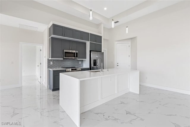 kitchen featuring a center island with sink, stainless steel appliances, light countertops, gray cabinetry, and a sink