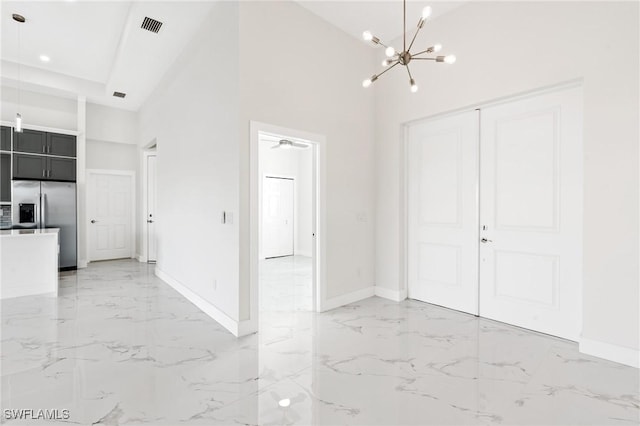 interior space featuring marble finish floor, a high ceiling, baseboards, and a notable chandelier