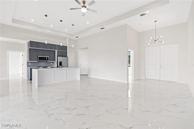 kitchen with pendant lighting, appliances with stainless steel finishes, light countertops, and open floor plan