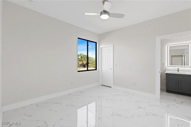 unfurnished bedroom featuring baseboards, ceiling fan, ensuite bathroom, marble finish floor, and a sink