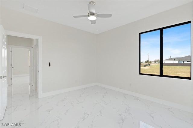 unfurnished room with a ceiling fan, marble finish floor, and baseboards