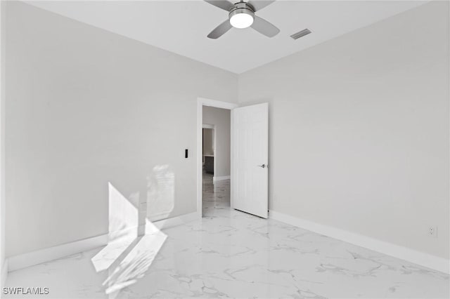 empty room featuring ceiling fan, marble finish floor, visible vents, and baseboards