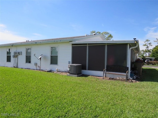 rear view of house with a sunroom, cooling unit, and a yard