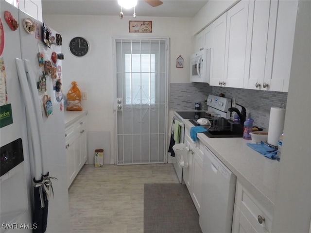 kitchen featuring light countertops, light wood-style flooring, backsplash, white cabinets, and white appliances