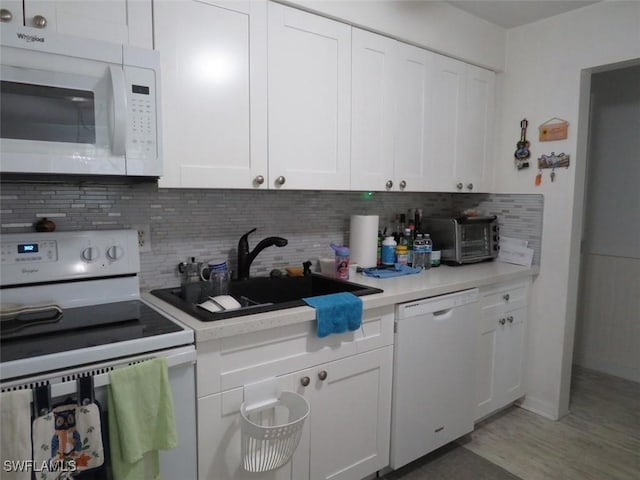 kitchen with light countertops, white appliances, white cabinets, and backsplash