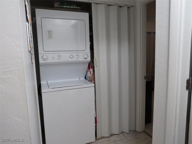 laundry area featuring laundry area, light wood finished floors, and stacked washing maching and dryer