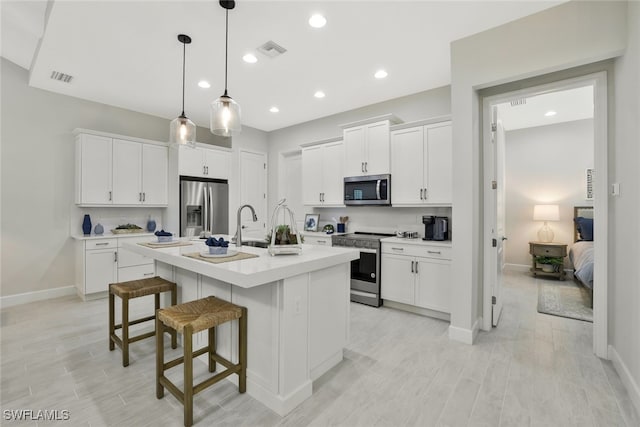 kitchen with white cabinetry, a kitchen island with sink, and stainless steel appliances