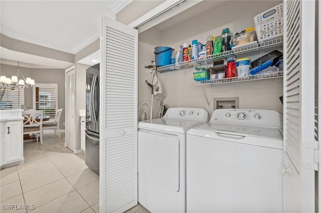 laundry area with light tile patterned floors, washing machine and dryer, laundry area, ornamental molding, and an inviting chandelier