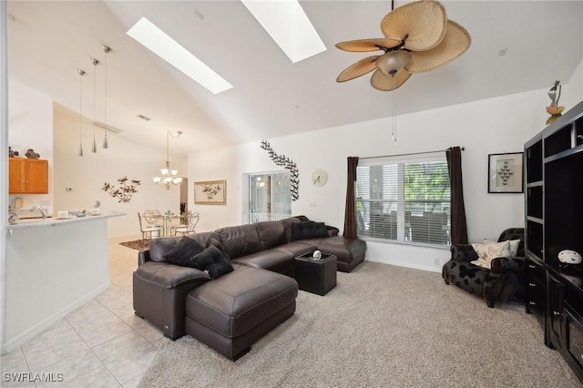 tiled living room with ceiling fan with notable chandelier, high vaulted ceiling, sink, and a skylight