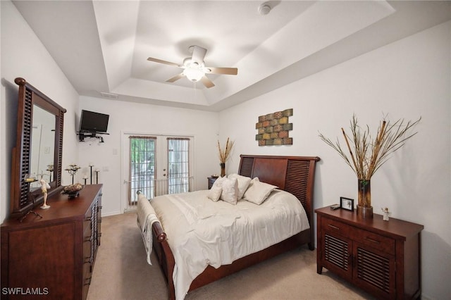 bedroom with access to outside, a raised ceiling, french doors, and light carpet