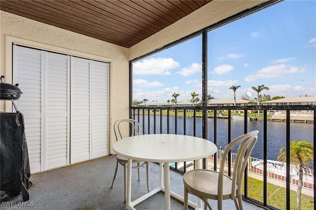 sunroom / solarium featuring a water view and wood ceiling