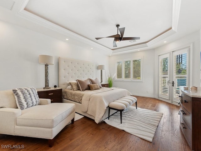 bedroom with dark wood finished floors, visible vents, a tray ceiling, and access to outside