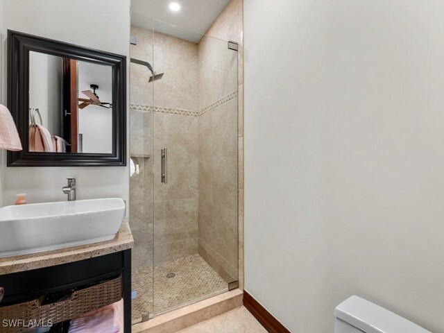 full bathroom with tile patterned floors, toilet, a shower stall, baseboards, and vanity