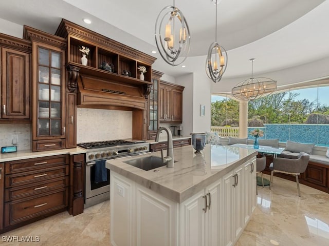 kitchen featuring a sink, backsplash, high end range, and hanging light fixtures