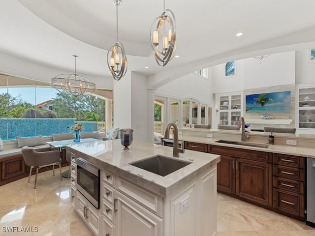 kitchen featuring light stone counters, a center island with sink, appliances with stainless steel finishes, and a sink