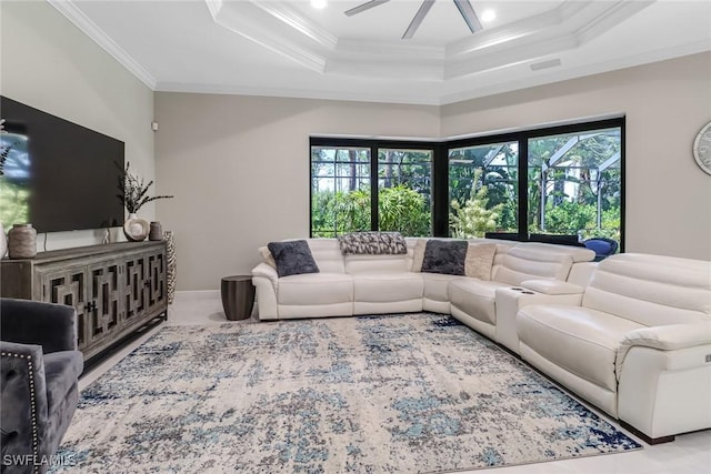 living room featuring a raised ceiling, ceiling fan, and crown molding