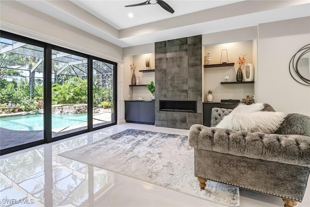 living room with ceiling fan and a tiled fireplace