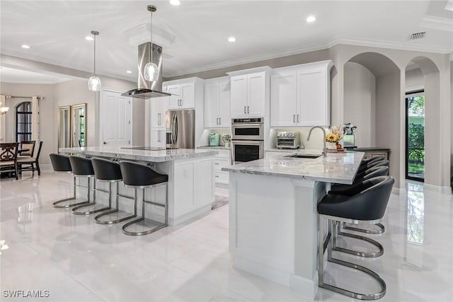 kitchen featuring a breakfast bar area, stainless steel appliances, decorative light fixtures, island range hood, and white cabinetry